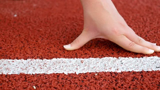 Close detail of track runner woman putting hands at starting line