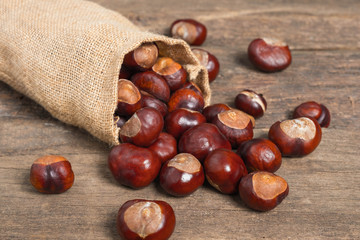 Chestnuts in jute sack on wooden background
