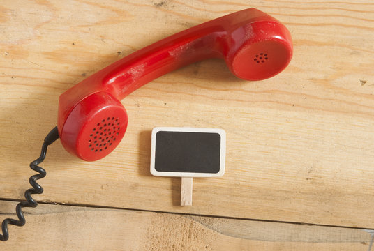 Red old fashioned telephone receiver on wooden table