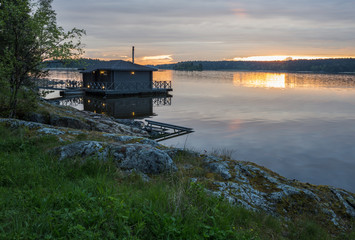 Fototapeta na wymiar Landscape with a house on the lake in Karelia at sunset