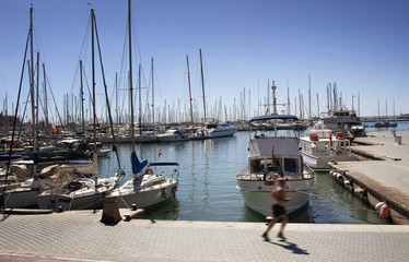 Man runs by Palma de Mallorca marina. Many yachts parked. It's a resort city and capital of the...