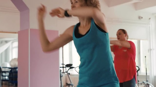Energetic group of women dancing aerobics, losing weight in the gym.
