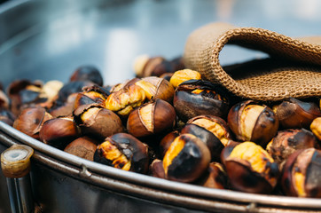 Close up of chestnuts on a pan with a salesman on the background