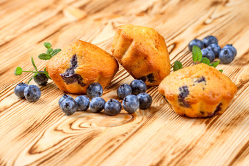 Blueberry muffin. Homemade baked cupcake with blueberries, fresh berries, mint on wooden background. Empty space for text.