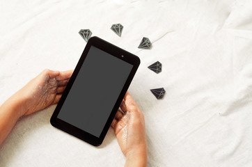 The hands hold the tablet. diamonds on the background.