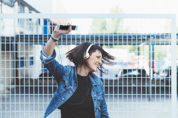 brunette girl with headphones and smartphone in the street dancing