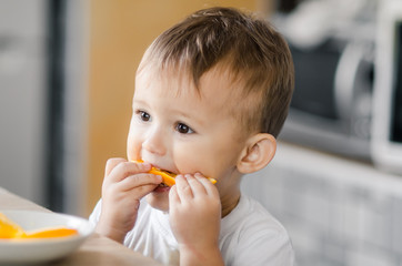 The child in the kitchen eating an orange