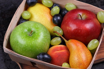 Red apple, dark blue grapes, green apple, yellow pear, green grapes, orange peach in a wooden box on a metallic background in retro style