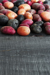 Wooden background with mix of fresh colorful potatoes