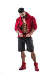 Muscular bodybuilder undressing, opening red hoodie sweater on naked muscle torso on light background