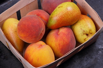 Yellow pears and orange peaches in a wooden basket with Christmas tree branches for Christmas dinner