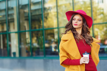 Young beautiful women in a yellow coat and a red hat, outdoor