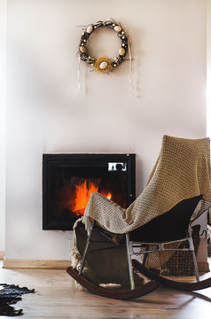 Rocking chair with knit rug before fireplace