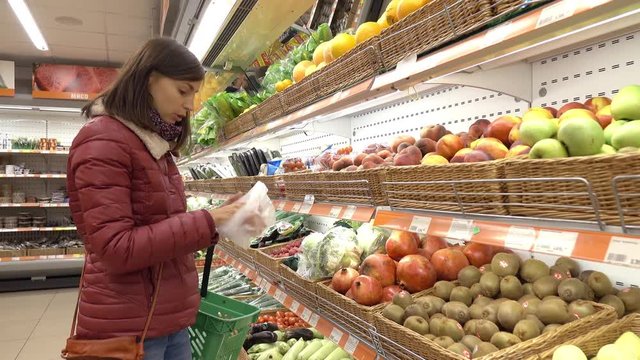 Woman in supermarket selects fruit and vegetables.