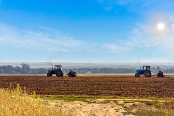 Beautiful agricultural landscape with two old tractors equipped with seeders. Farmers sowing winter wheat in autumn.