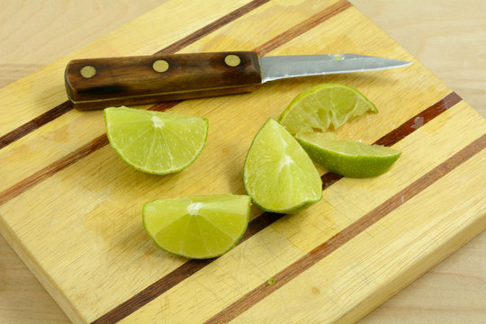 Lime wedges on wooden cutting board with knife