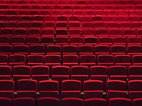 Rangées de fauteuils rouges dans une salle de spectacle