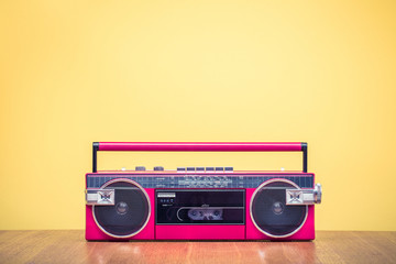 Retro outdated red portable stereo radio cassette recorder from 80s front yellow background....