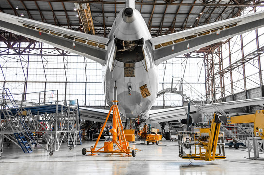 Fototapeta Large passenger aircraft on service in an aviation hangar rear view of the tail, on the auxiliary power unit.