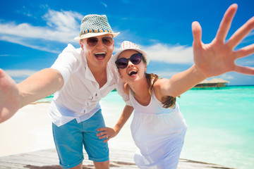 happy young couple in white clothes having fun by the beach