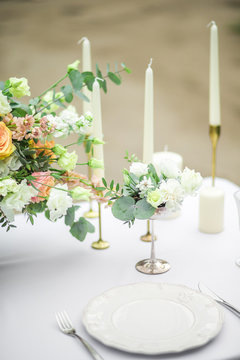decorated wedding table for two with beautiful flower composition, glasses for wine, candles and plates, outdoor, fine art.