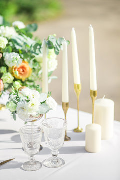 decorated wedding table with beautiful flower composition, candles and glasses, outdoor, fine art.
