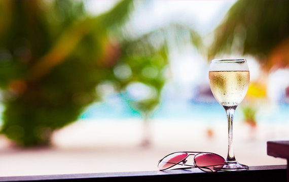 glass of chilled white wine on table near the beach