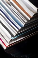 Used magazines - books stacked in a pile on a black background.