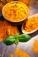 Composition with bowl of turmeric powder on wooden table
