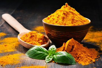 Composition with bowl of turmeric powder on wooden table