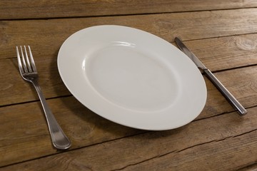 White plate with cutlery and napkin on table