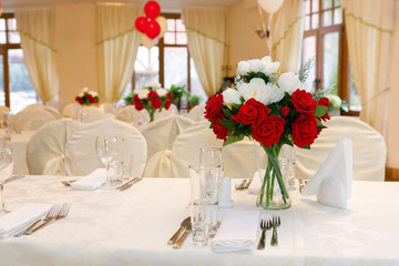 Beautifully set festive table, decorated with a bouquet of roses. The preparations for the party