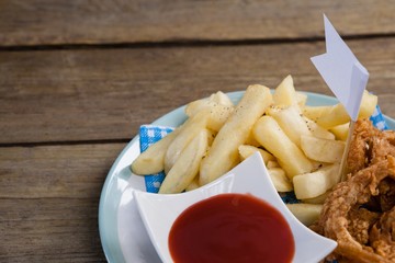 Onion ring and french fries with ketchup arranged in plate