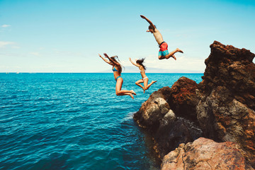 Friends cliff jumping into the ocean