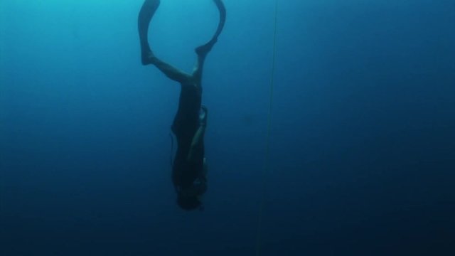 Person free dives in deep ocean, POV