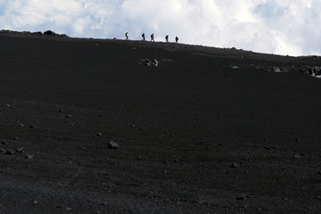 Tourists silhouettes on the edge of path on Mount Etna, Sicily, Italy
