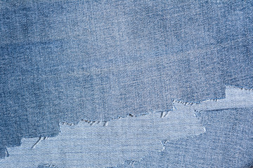 Fototapeta na wymiar shreds of denim fabric, unevenly cut jeans