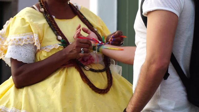 Baiana Welcoming the Tourist giving some "Brazilian Wish Ribbons" in Salvador, Brazil - the ribbons are considered good luck charms