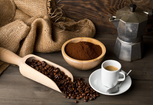 Coffee beans, ground coffee powder and cup of espresso with stovetop coffee maker