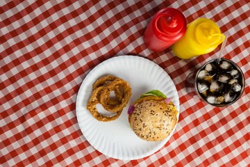 Hamburger, french fries, onion ring and cold drink on napkin