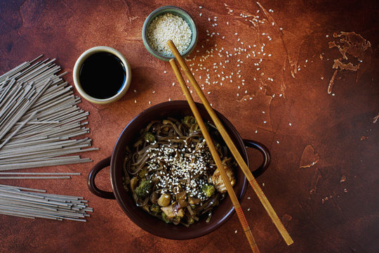 Asian dish with soba noodls, chicken, green onions, broccoli, soy sauce and sesam seeds