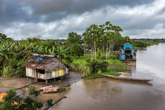 Closeup view of Amazon village shack and large blue boat