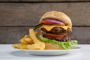 Hamburger and french fries in plate on wooden table