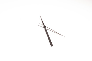 two crossed tweezers for eyelash extension on the white background