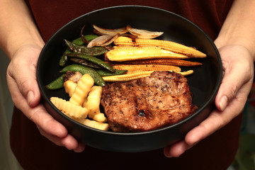 Pork steak with mixed vegetable on white dish.