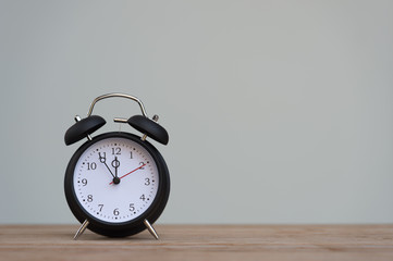 Retro alarm clock with five minutes to twelve o'clock.