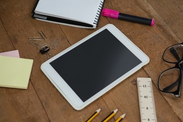 School supplies, digital tablet and spectacles on wooden table