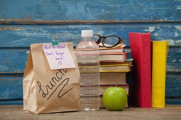Stack of books, apple, water bottle, spectacles and lunch bag © wavebreak3