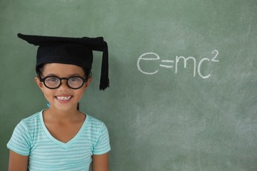 Young girl with graduation hat against chalk board