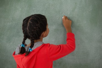 Young girl writing on chalk board